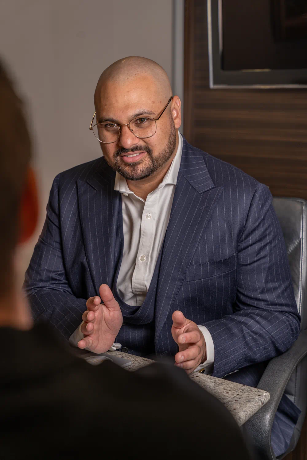 Man in suit engaging in conversation at desk.